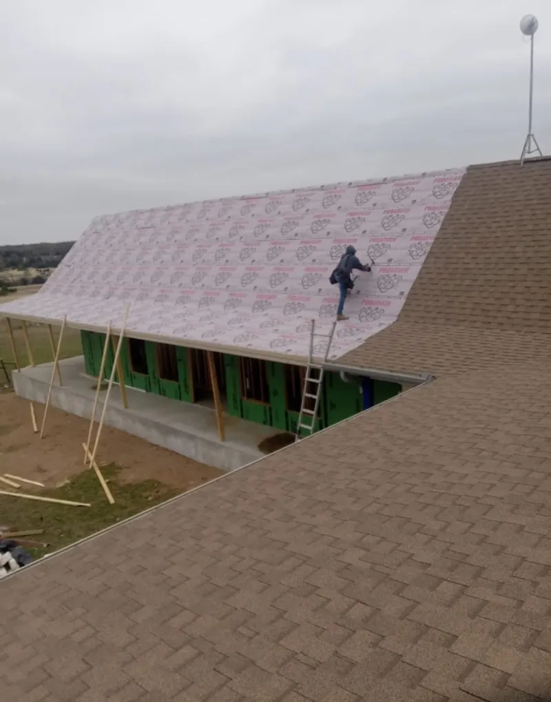 Worker preparing underlayment for a metal roof installation in North Bend